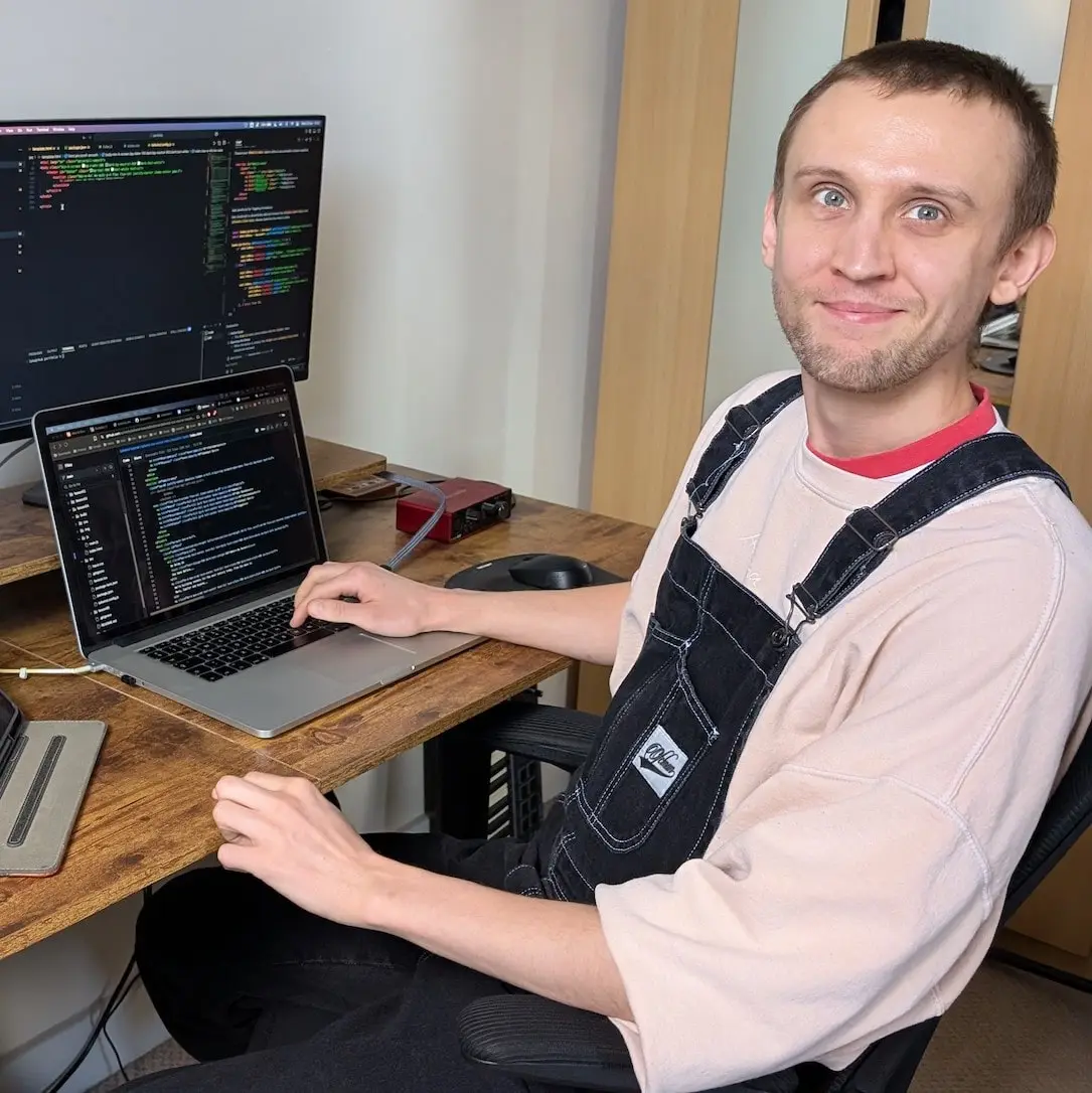 A picture of me smiling at the camera whilst working at my desk.